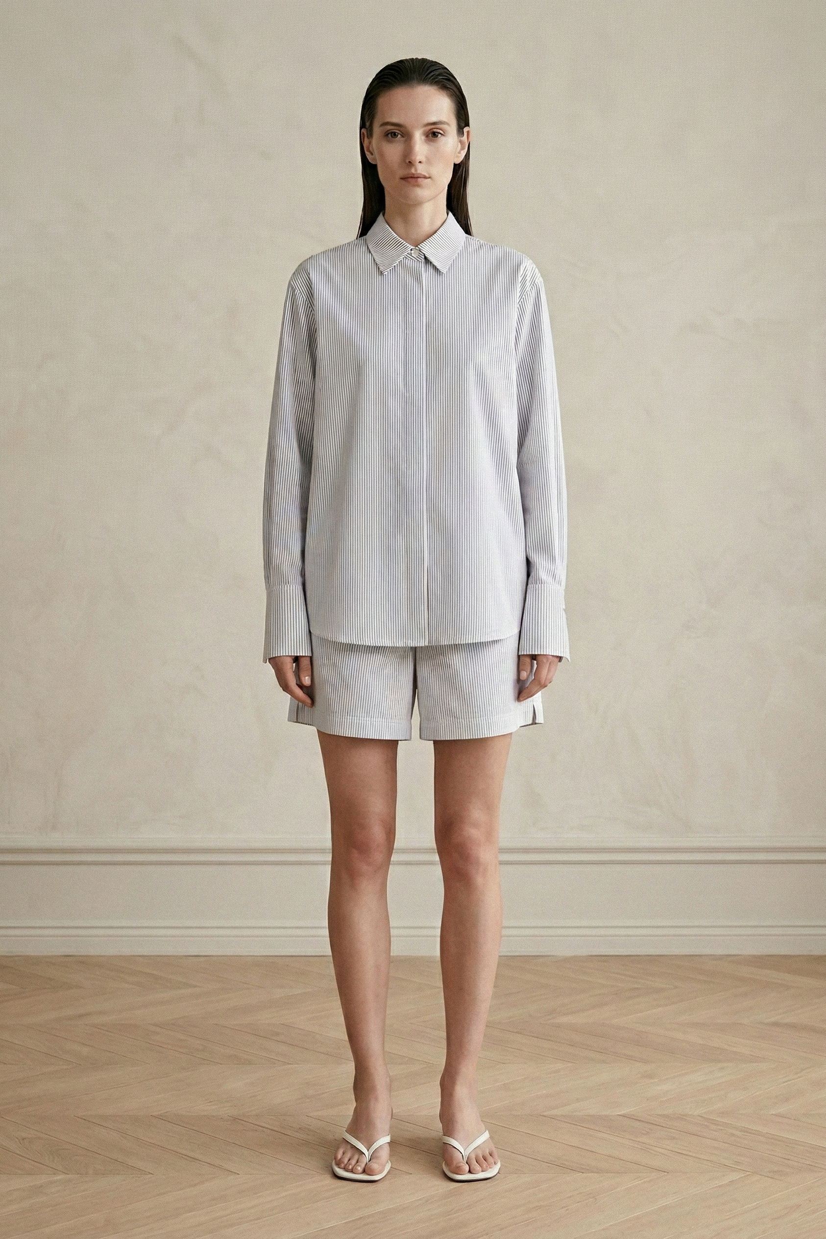 Woman wearing a light blue shirt and beige shorts against a neutral background