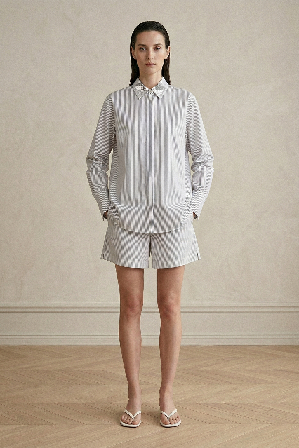 Woman wearing a light gray shirt and shorts against a plain background
