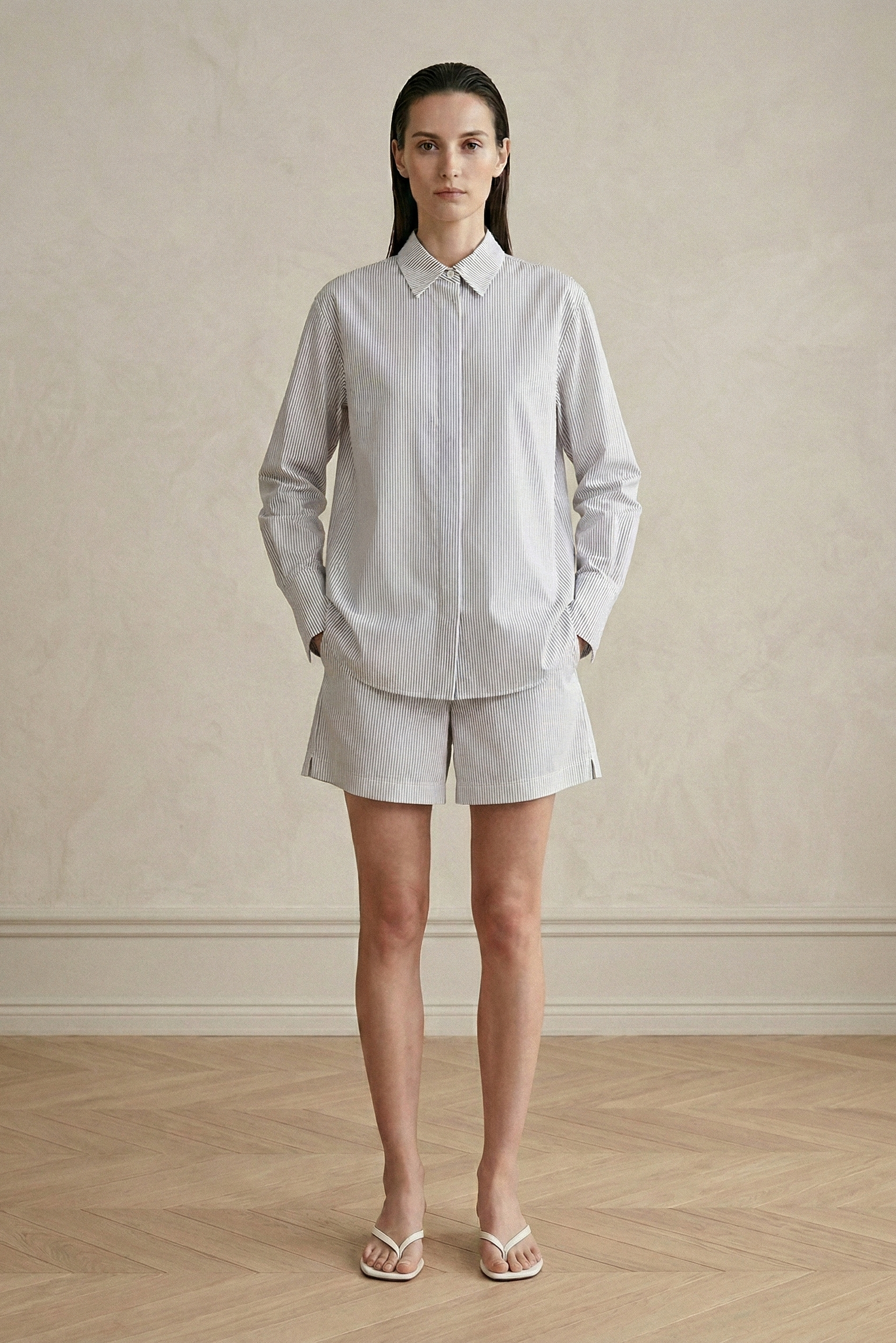 Woman wearing a light gray shirt and shorts against a plain background