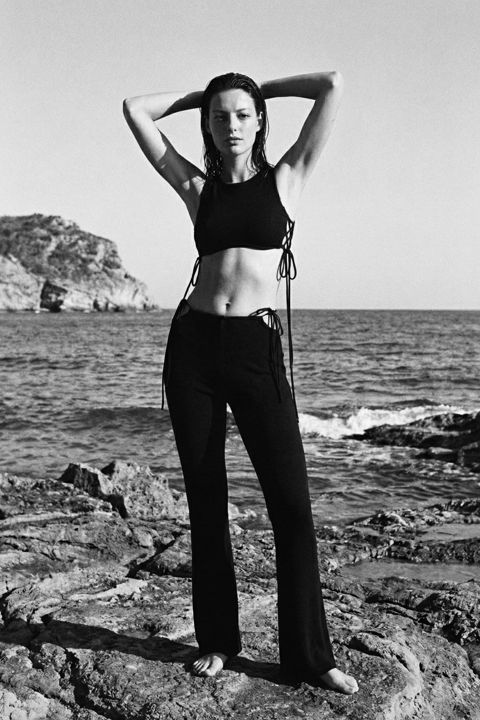 Person standing on rocky beach with ocean and cliffs in the background